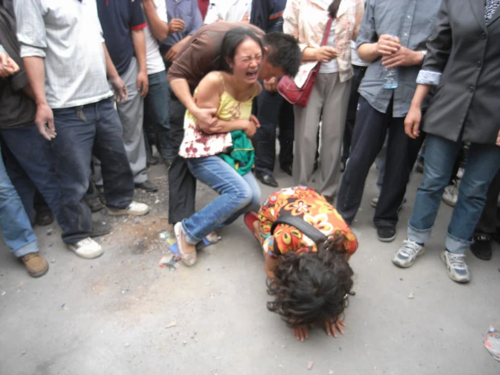 Daughters kneel and beg for their father to be rescued from a collapsed building. He was later found dead. 2008 Sichuan Earthquake, at Dujiangyan, China.