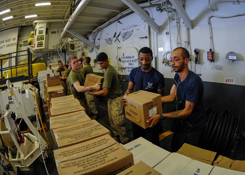 160604-N-GZ228-181 GULF OF ADEN (June 4, 2016) Sailors and Marines work together to transport incoming food and supplies in the hangar bay of amphibious assault