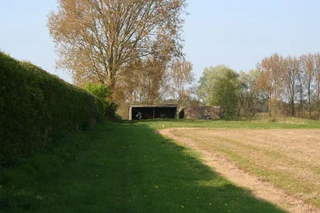 Getting a clearer view The pillbox gets clearer as you get nearer to it and can be seen sat next to a small open shed.