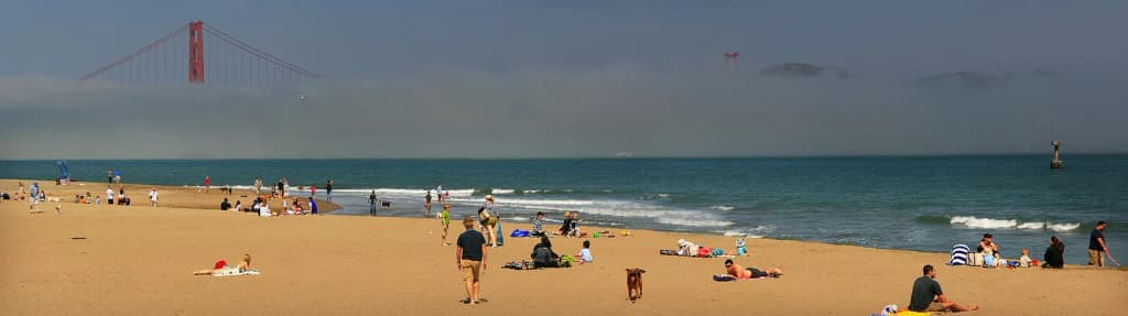 Crissy Field beach on San Francisco Bay with Golden Gate Bridge . The bridge is obscured by famous San Francisco fog .