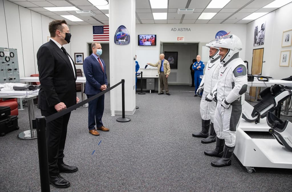 Behind the rope, SpaceX CEO and Chief Designer Elon Musk (left) and NASA Administrator Jim Bridenstine greet NASA astronauts Robert Behnken (left) and Douglas H