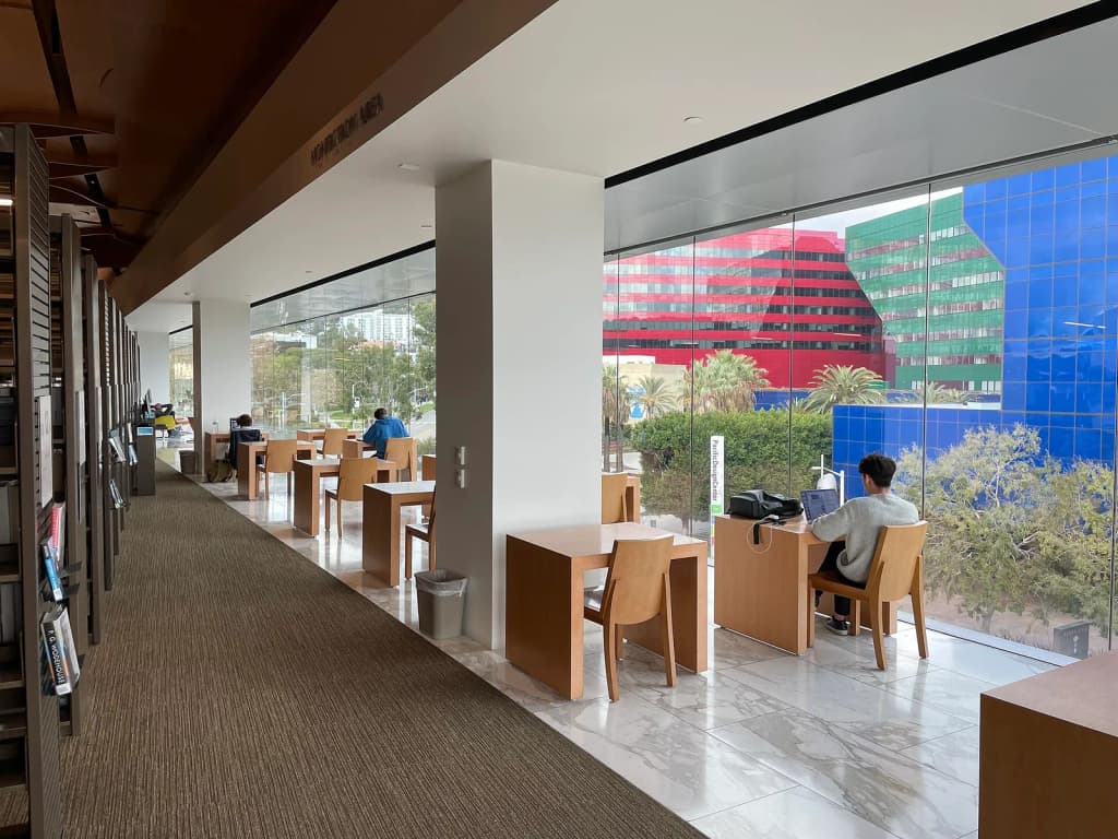 Reading area and some stacks at the West Hollywood Library in December 2023. Pacific Design Center is in the background.
