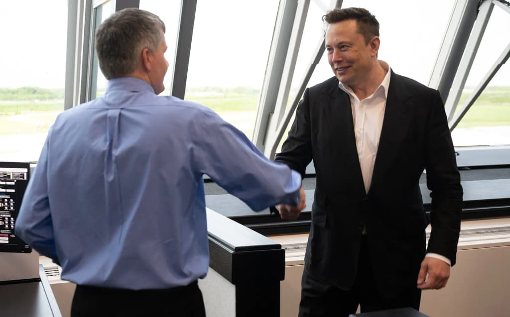 Elon Musk, SpaceX Chief Engineer, shakes hands with Steve Stich, deputy manager of NASA’s Commercial Crew Program, following the launch of a SpaceX Falcon 9 roc