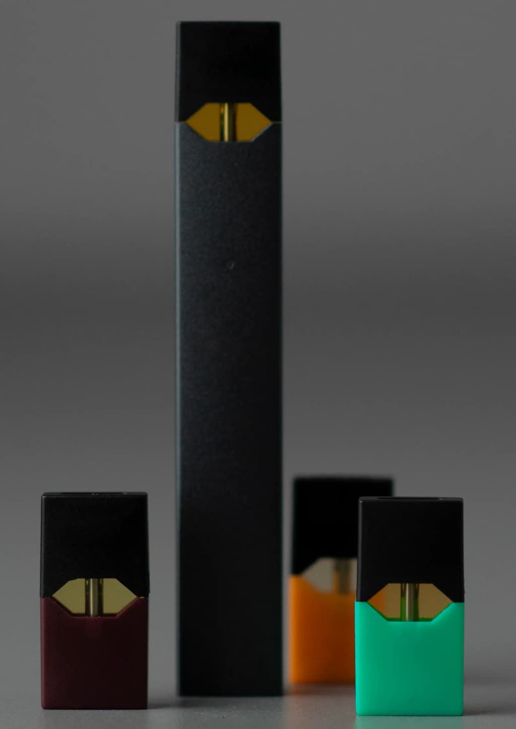 A Juul electronic cigarette, with four 'pods' (one loaded and three next to it).